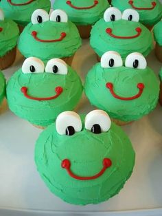 cupcakes with green frosting and red eyes are arranged on a white plate