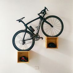 a bicycle mounted to the wall with two wooden boxes holding it's wheels and helmet