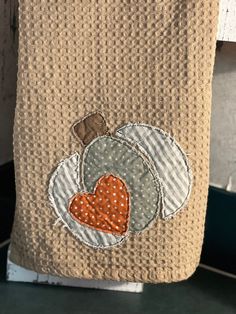 a towel hanging on the side of a door with a pumpkin and heart applique