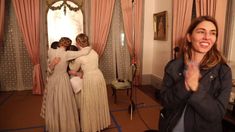 two women are hugging in front of a mirror while another woman is taking a selfie