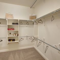 an empty walk in closet with clothes hanging on the shelves