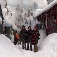 three people standing in the snow near a building