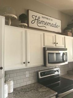 a kitchen with white cabinets and black stove top oven next to a sign that says happiness is homemade