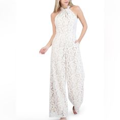 Beautiful Knot Neck Halter Lace Jumpsuit In An Ivory Lace With Nude Lining. Slight Wide Leg, With Side Seam Pockets, Zipper At Center Back With Key Hole And Button Closure At Neck, Fully Lined. 100% Polyester, Hand Wash, With Like Colors, Line- Dry. Elegant Lace Jumpsuits And Rompers For Spring, Lace Jumpsuits And Rompers For Wedding, Beige Jumpsuits And Rompers For Evening, Elegant Cream Jumpsuits And Rompers For Party, Feminine Fitted Jumpsuits And Rompers For Formal Occasions, Feminine Fitted Jumpsuit For Formal Occasions, Elegant Cream Jumpsuit For Party, White Fitted Feminine Jumpsuits And Rompers, Spring Cream Party Jumpsuits And Rompers