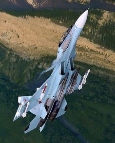 a fighter jet flying through the sky over mountains