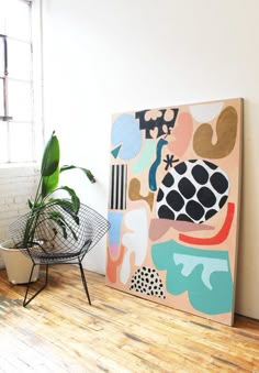 a painting on the wall next to a potted plant in a room with white walls