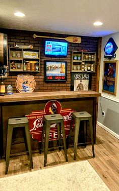 a bar with three stools in front of it and several sports memorabilia on the wall