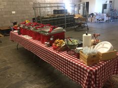 a long table covered in red and white checkered cloths with food on it