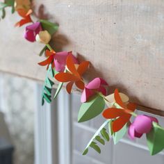 some paper flowers hanging from a window sill