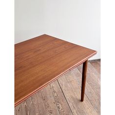 a wooden table sitting on top of a hard wood floor next to a white wall