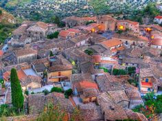 an aerial view of a village in the mountains with red tile roofs and green trees