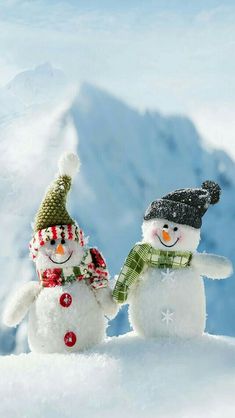 two snowmen standing next to each other in the snow