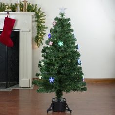 a small green christmas tree sitting in front of a fireplace