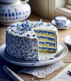 a blue and white cake sitting on top of a plate next to a cup filled with tea