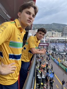 two young men standing next to each other in front of a stadium filled with people