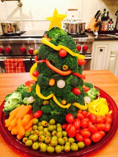 a christmas tree made out of vegetables on a red plate in the middle of a kitchen