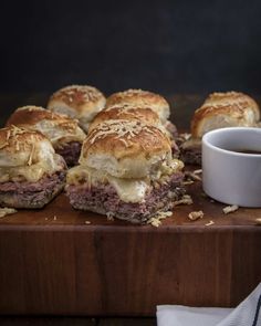 several pastrami sliders on a cutting board with a cup of coffee in the background