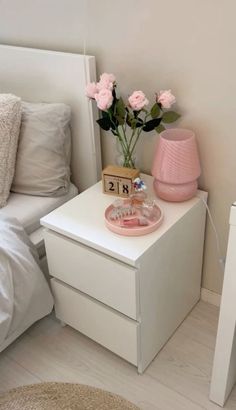 a white nightstand with pink flowers on it and a clock next to the night stand