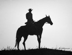 a man riding on the back of a horse next to a tall grass covered hill