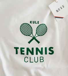 a white shirt with green tennis rackets on it and a tag that says kule tennis club