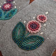 two handmade beaded flowers sitting on top of a gray felt covered coasters