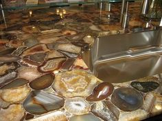 a kitchen counter top covered in lots of rocks and stones, with a metal sink