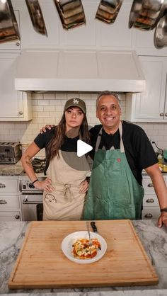 a man and woman standing in a kitchen next to a cutting board with food on it