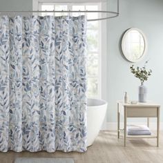 a bathroom with a bathtub, rug and shower curtain that has blue leaves on it