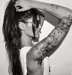 a woman with long hair and tattoos on her arm is posing for a photo in black and white