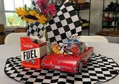 a table topped with a red car covered in candy and candies next to a vase filled with flowers