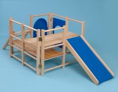 a wooden play set with a slide and blue seats on the bottom floor, against a light blue background