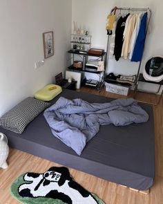 an unmade bed sitting on top of a hard wood floor next to a closet