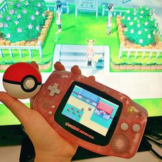 a person holding a nintendo wii game controller in front of a tv with pokemon on it