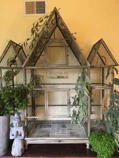 a house made out of metal with plants in the foreground and a potted plant next to it