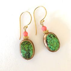 "Beautiful genuine green turquoise gemstones edged in golden copper with pale orange coral accent on 24k gold vermeil ear hooks. Artisan lime green turquoise gemstones are natural 17 x 12 x 6mm oval stones edged in golden copper. Each side has unique matrix patterns giving it a lovely rustic appearance. 4mm natural coral rounds in pale orange add pop of color. Accented with 24k gold vermeil spacer beads. Lightweight earrings hang from 24k gold vermeil artisan ear wires. Total length is 1 1/2\"." Gold Bohemian Jewelry With Malachite, Gold Bohemian Malachite Jewelry, Artisan Green Copper Jewelry, Turquoise Gemstone Brass Jewelry, Handmade Turquoise Chrysoprase Jewelry, Oval Green Brass Jewelry, Artisan Turquoise Earrings With Natural Stones, Turquoise Jade Earrings With Natural Stones, Green Artisan Gemstone Earrings