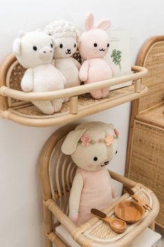 three stuffed animals sitting on top of a bamboo shelf next to a basket with wooden spoons