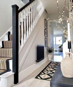 a white vase sitting on top of a wooden table next to a stair case in a house