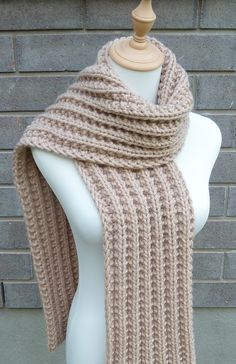 a white mannequin wearing a beige knitted scarf