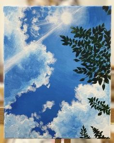 an easel with a painting on it that has clouds and trees in the sky