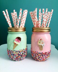 two mason jars with ice cream and sprinkles on them, one is filled with paper straws