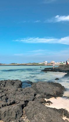 the beach is covered with rocks and clear blue skies are visible in the distant distance