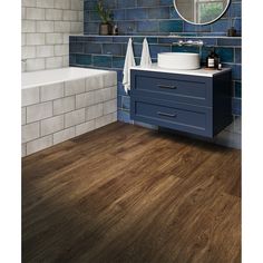 a bathroom with blue tile and wood flooring on the walls, along with a white bathtub