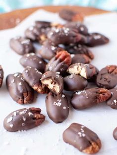 chocolate covered pecans with nuts scattered around them