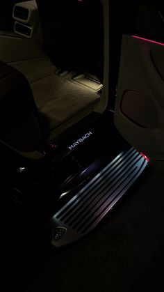 the interior of a vehicle with its door open and lights on in the dark room