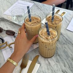 two people are holding their glasses with drinks in them on the table next to each other