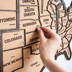 a person is writing on a cork board map