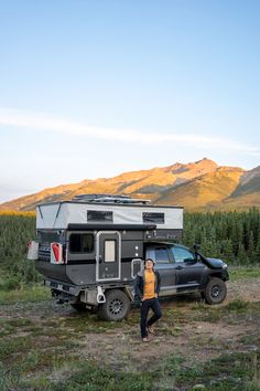 a person standing next to a truck with a camper in the background