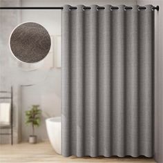 a gray shower curtain next to a white tub in a bathroom with a round mirror on the wall