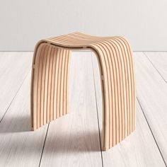 a wooden stool sitting on top of a hard wood floor next to a white wall