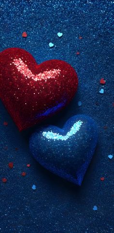 two blue and red heart shaped candies with confetti scattered around them on a dark blue background